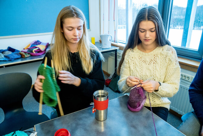 Bilde av to jenter som sitter ved et bord og strikker sammen. Strikkekafe på Rosenvilde.